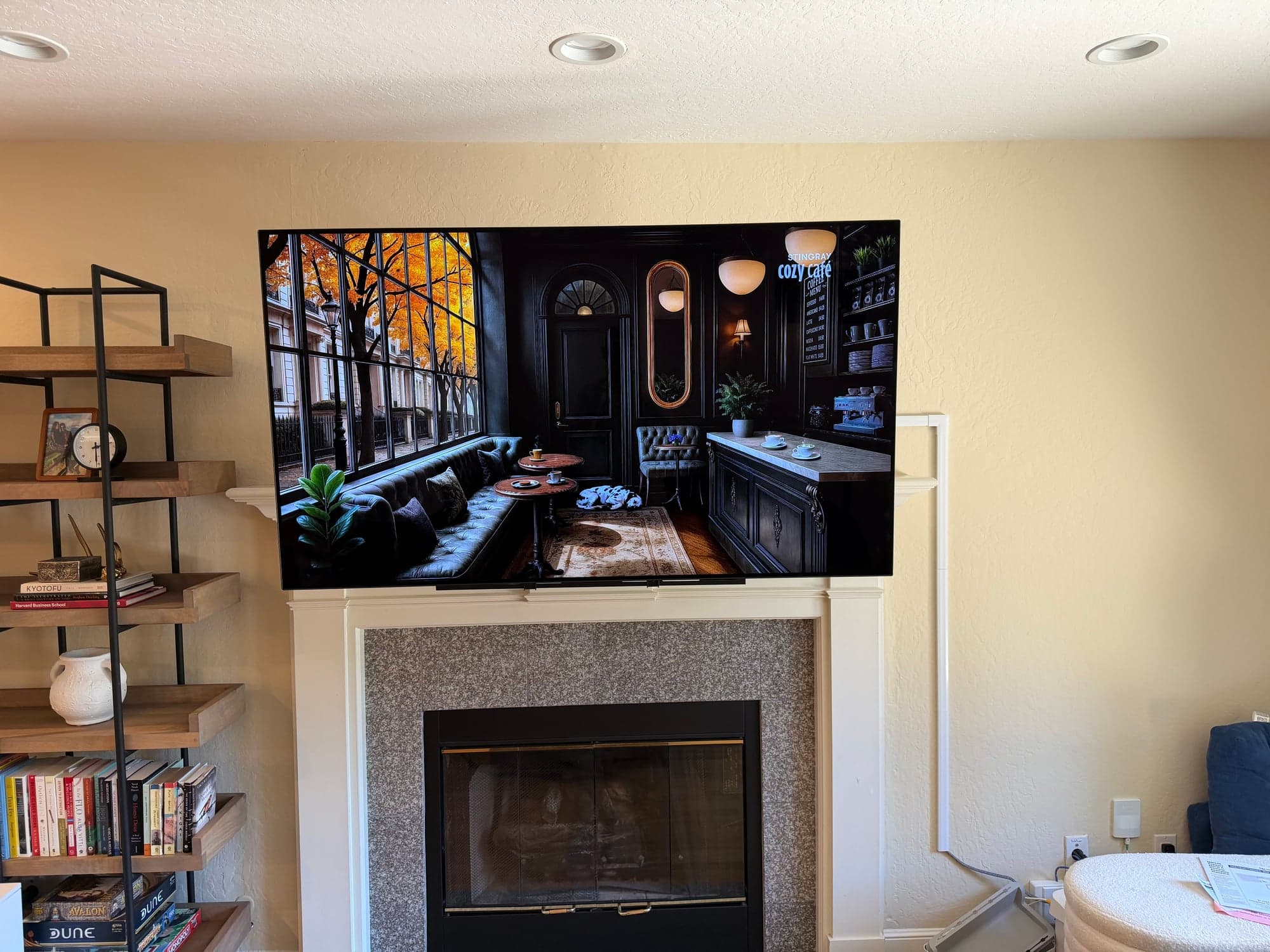 A flat screen TV mounted above a tiled fireplace mantel, showing an ambient screensaver