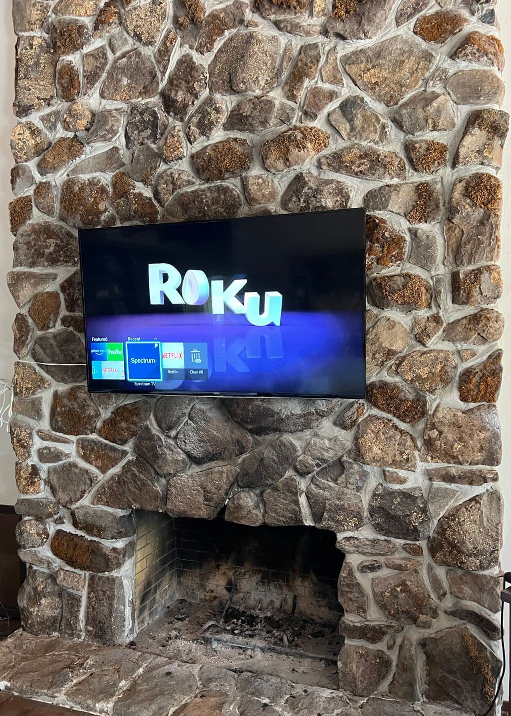 The same stone chimney breast with a flat screen TV mounted flush against it